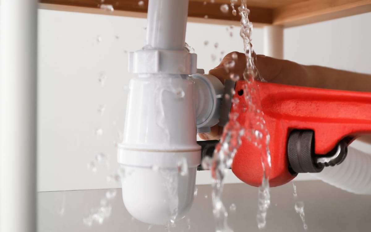 Emergency pipe leak spraying water under a sink