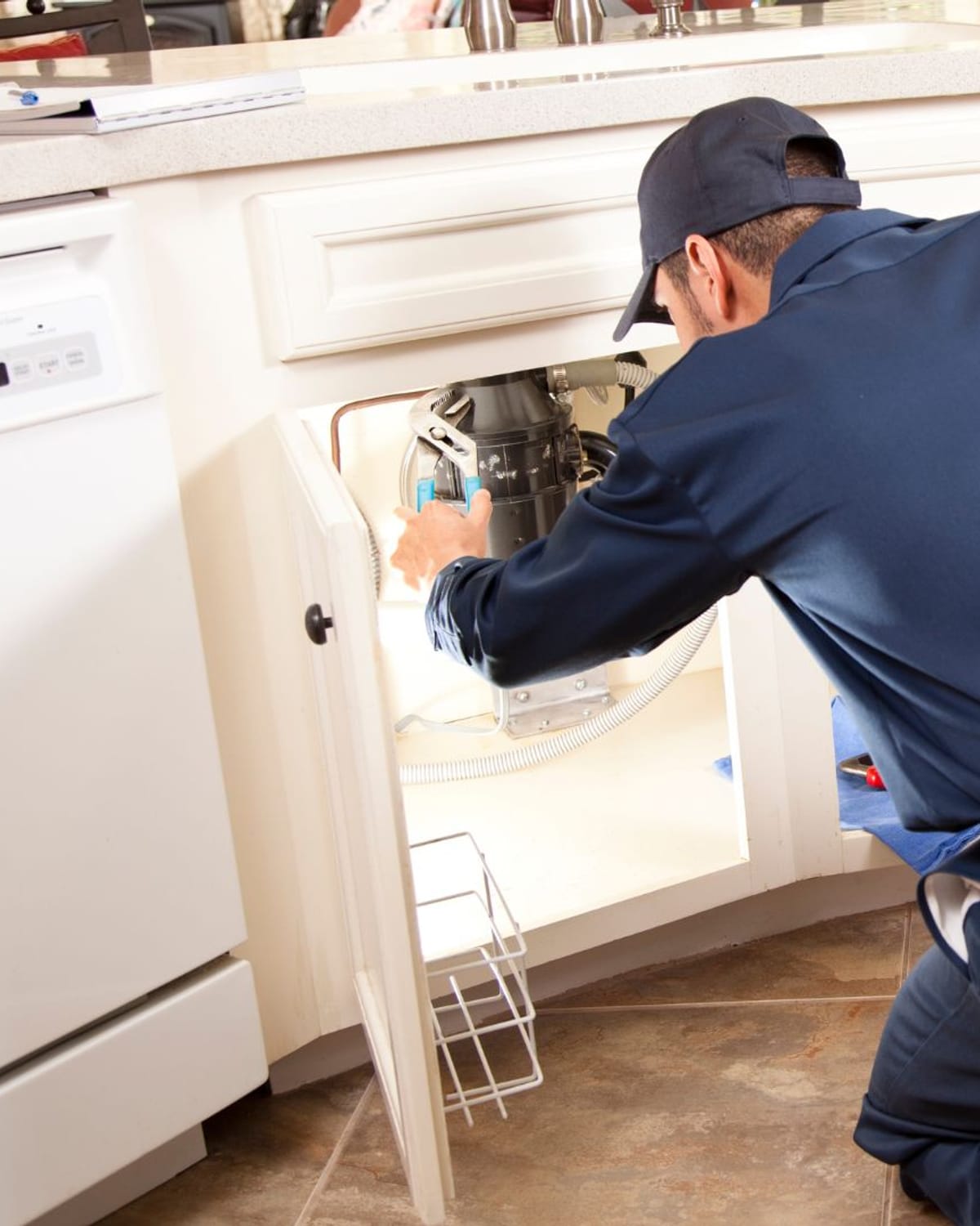 Plumber connecting a garbage disposal beneath a kitchen sink