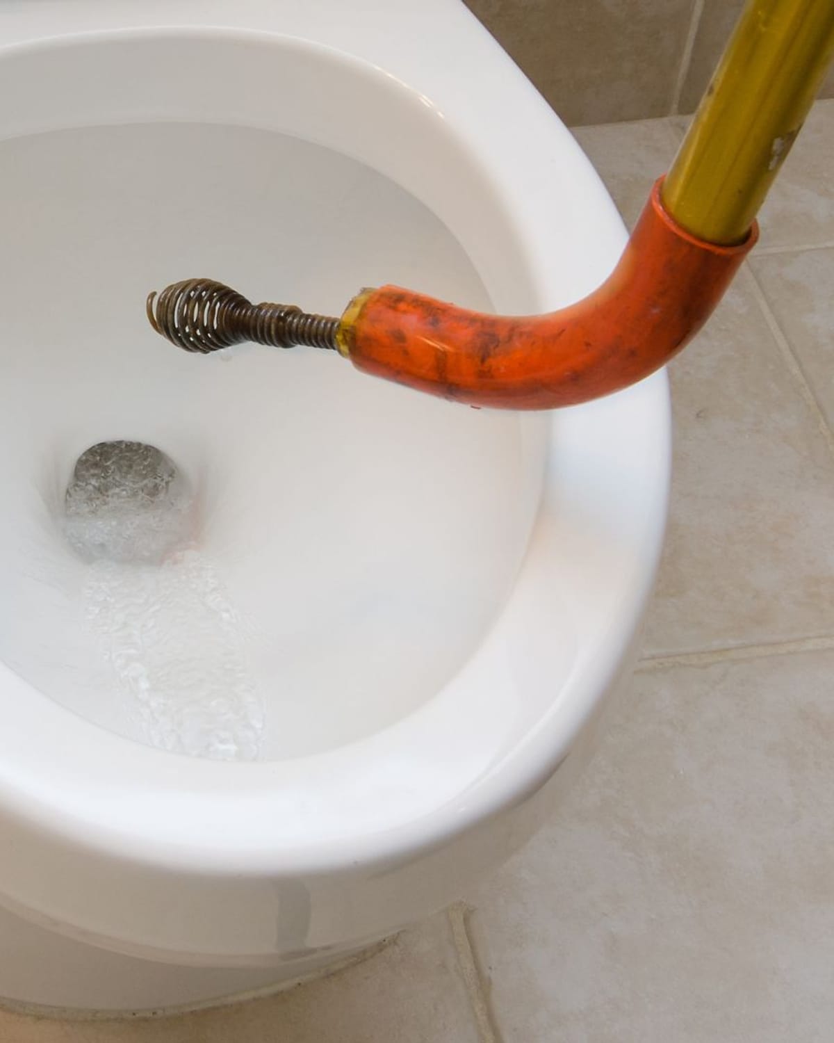 Drain auger clearing a clogged toilet line