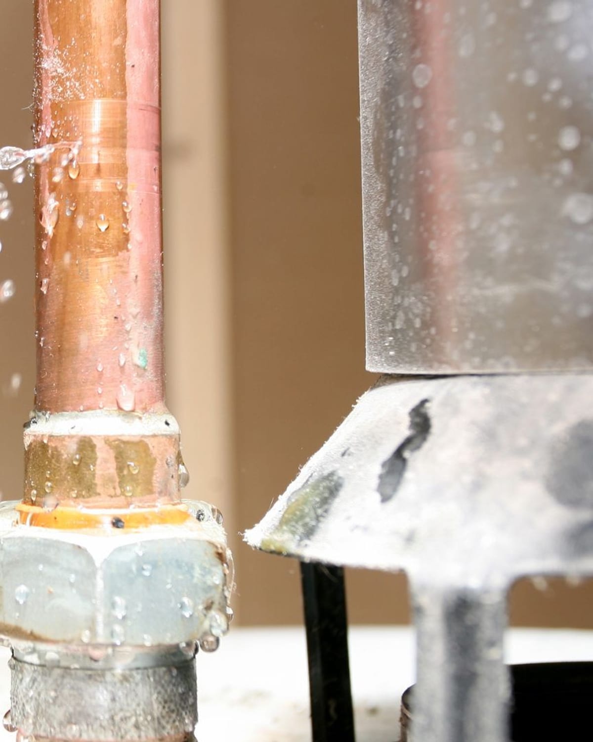 Burst copper pipe spraying water inside a wall cavity