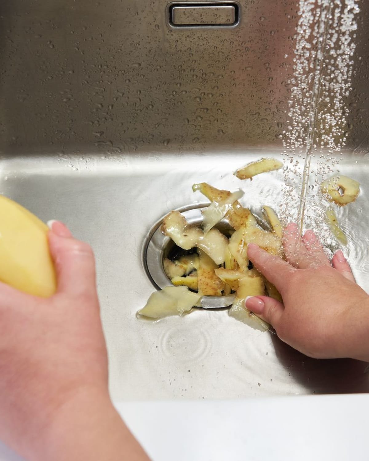 Food scraps being rinsed toward a kitchen disposal