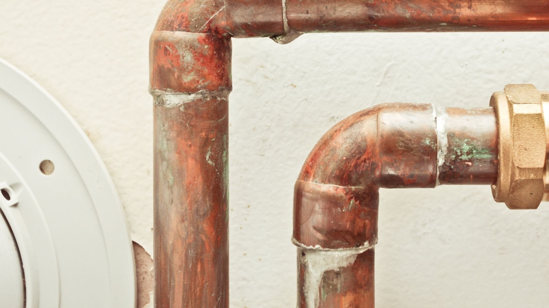 Weathered copper plumbing pipes with rust and connection joints
