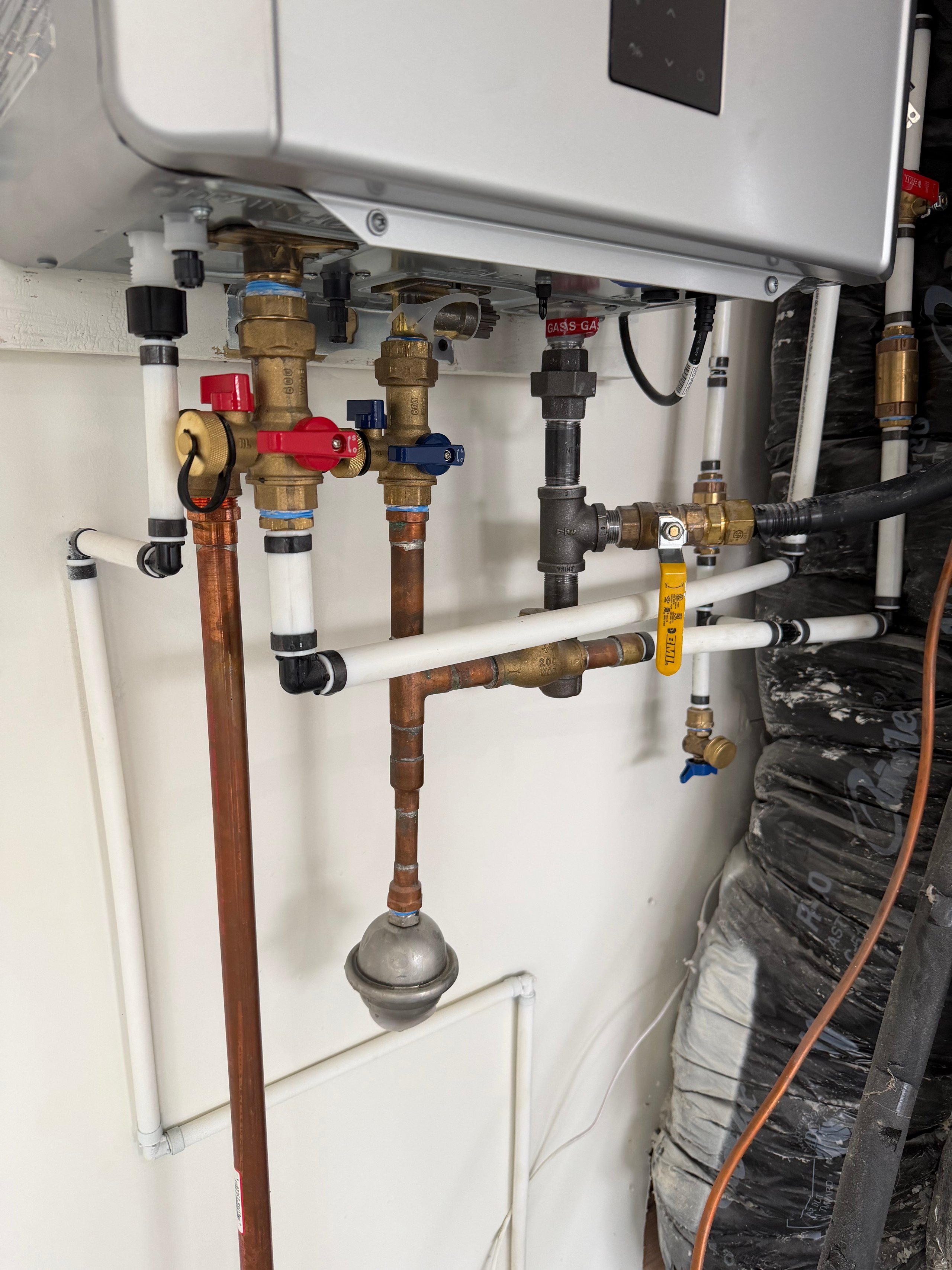 Complex plumbing installation with copper pipes, valves, and water heater