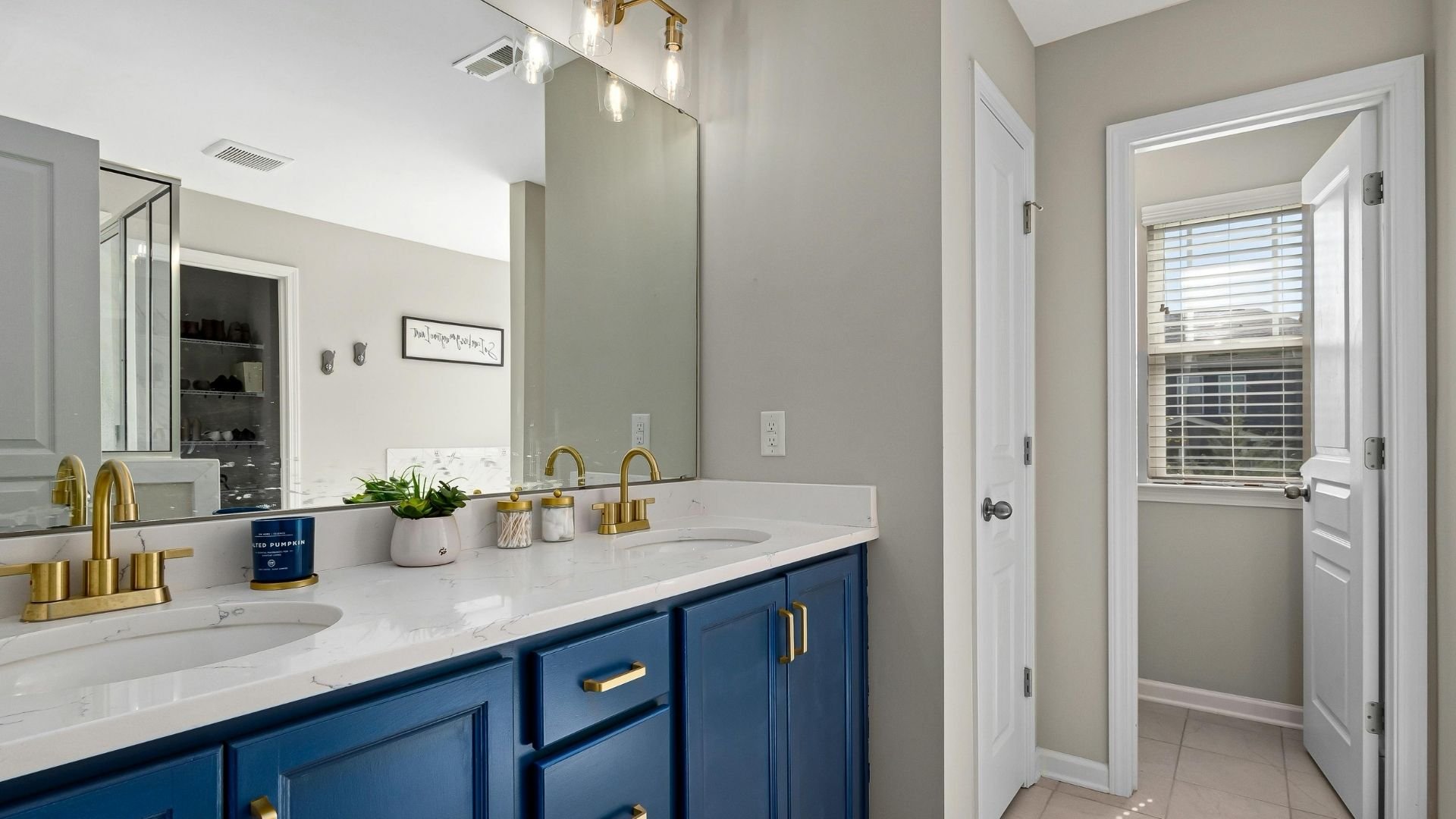 Modern bathroom with blue vanity, gold fixtures, and elegant plumbing design